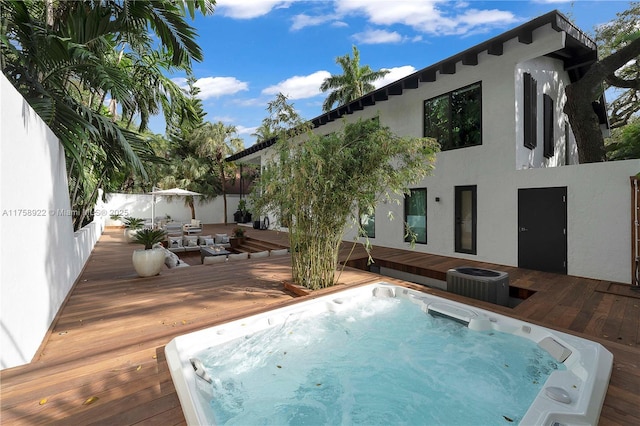 view of swimming pool with fence, cooling unit, a wooden deck, and hot tub deck surround