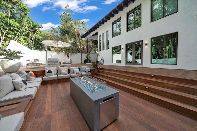 exterior space featuring an outdoor living space with a fire pit, a wooden deck, and fence