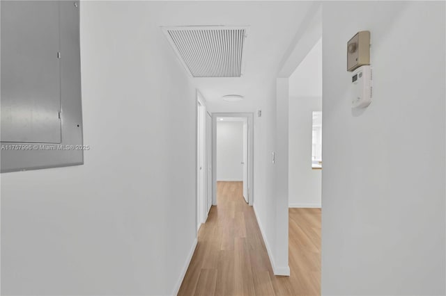 corridor featuring electric panel, visible vents, light wood-style flooring, and baseboards