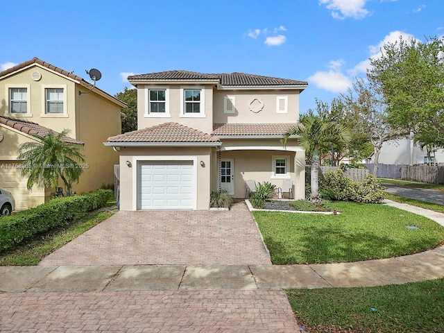 mediterranean / spanish-style home featuring decorative driveway, stucco siding, an attached garage, a front yard, and fence