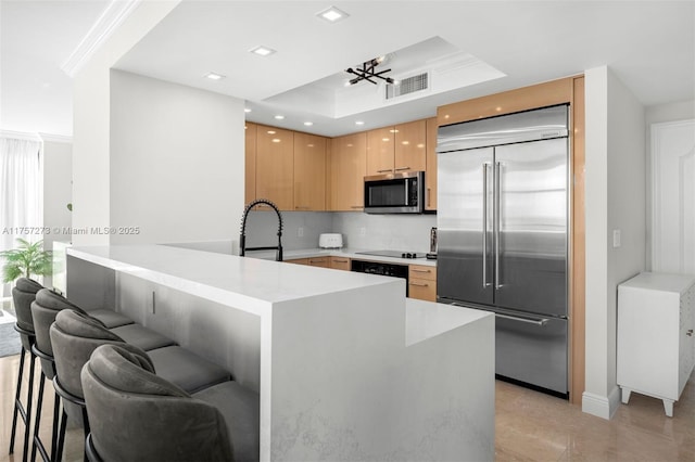 kitchen featuring visible vents, light countertops, appliances with stainless steel finishes, a peninsula, and a sink