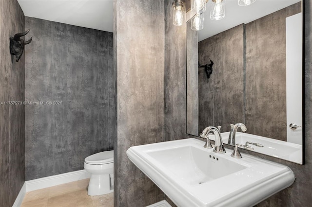 half bath with tile patterned flooring, toilet, baseboards, and a sink