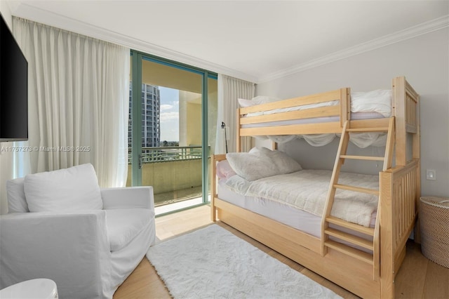 bedroom with a wall of windows, wood finished floors, ornamental molding, and access to outside