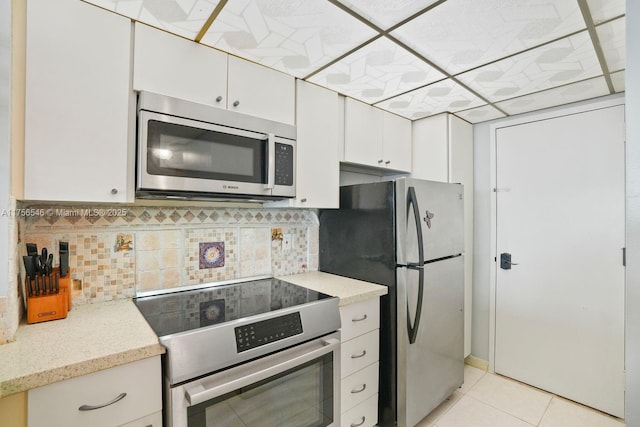 kitchen featuring appliances with stainless steel finishes, light tile patterned flooring, backsplash, and white cabinets