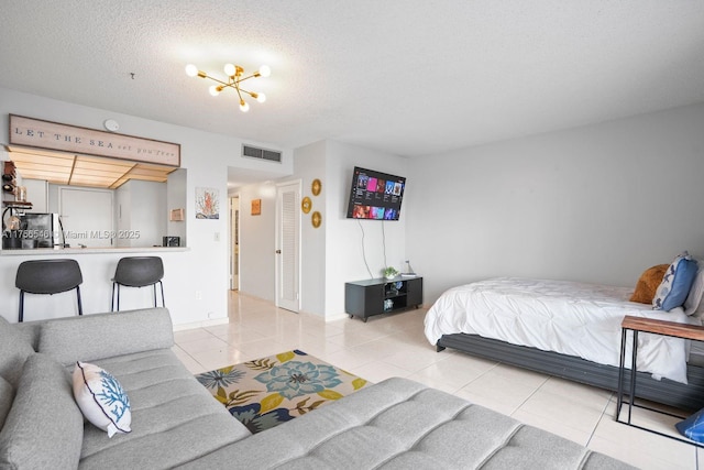 bedroom featuring tile patterned flooring, visible vents, and a textured ceiling