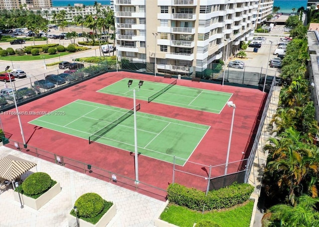 view of tennis court featuring a water view and fence