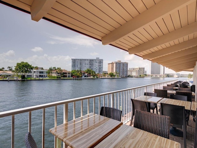 balcony with a view of city, outdoor dining area, and a water view