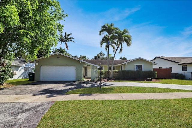 single story home featuring fence, an attached garage, stucco siding, a front lawn, and aphalt driveway