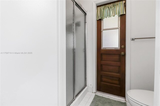 bathroom featuring tile patterned floors, a shower stall, and toilet