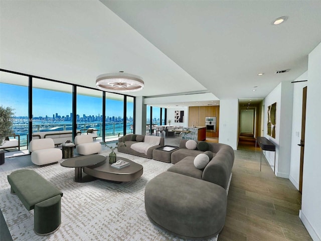 living area with a city view, recessed lighting, wood finished floors, visible vents, and baseboards