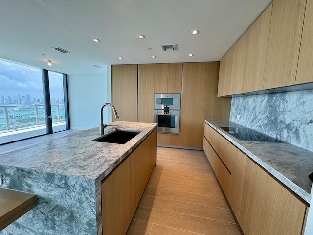 kitchen featuring visible vents, modern cabinets, black electric stovetop, and a sink