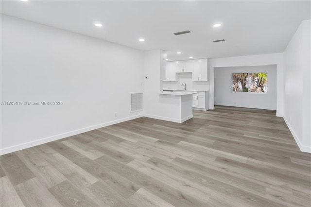 interior space with light wood-style flooring, visible vents, and a sink