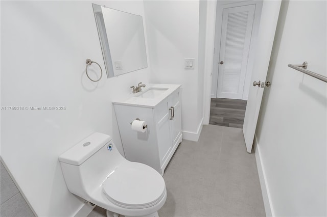 bathroom featuring toilet, tile patterned flooring, baseboards, and vanity