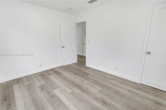 unfurnished bedroom featuring visible vents, baseboards, and wood finished floors