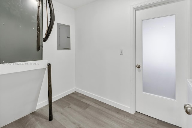 interior space with electric panel, baseboards, and wood finished floors