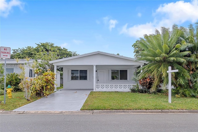 view of front of house featuring a front yard, concrete driveway, and stucco siding