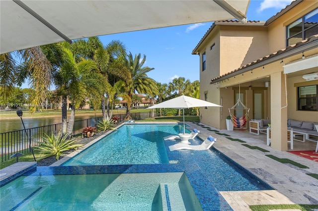 view of pool featuring a patio area, a pool with connected hot tub, a fenced backyard, and a water view