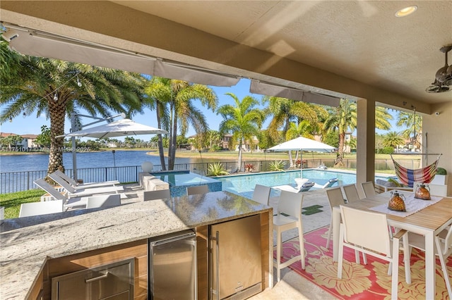 view of patio featuring a fenced in pool, a water view, outdoor wet bar, and fence