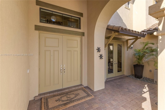 doorway to property with french doors, a tile roof, and stucco siding