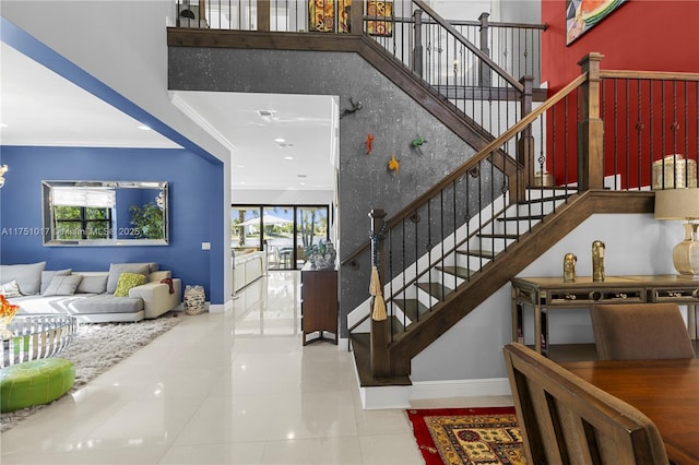 stairs with tile patterned floors, a high ceiling, baseboards, and ornamental molding