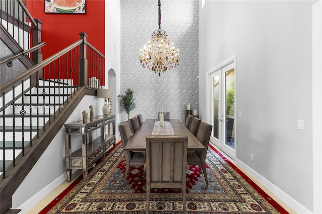 dining area featuring stairway, a high ceiling, an inviting chandelier, wallpapered walls, and an accent wall