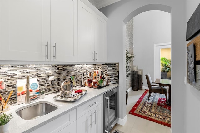 kitchen with wine cooler, arched walkways, tasteful backsplash, and a sink