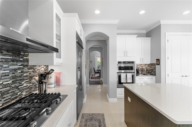 11360 NW 83rd Way, Parkland, FL 33076 - kitchen featuring white cabinets, arched walkways, backsplash, wall chimney range hood, and appliances with stainless steel finishes