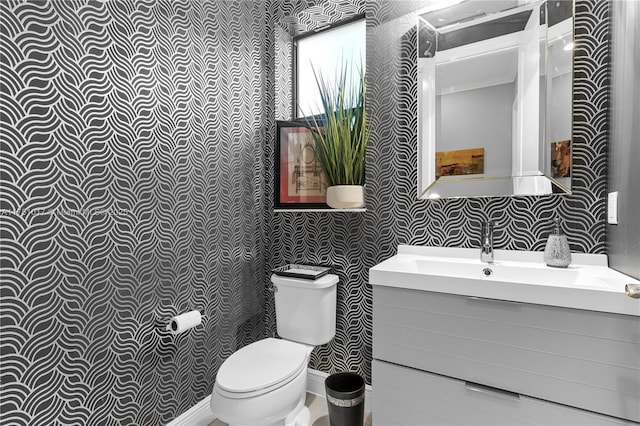 bathroom featuring toilet, wallpapered walls, and vanity