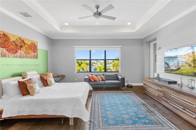 bedroom with a tray ceiling, visible vents, dark wood-style flooring, and crown molding