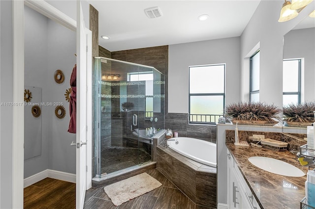 bathroom with visible vents, a stall shower, wood finished floors, a bath, and vanity