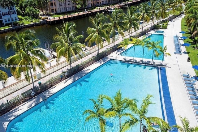 community pool with a water view and fence