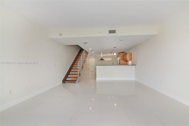 unfurnished living room with stairway, baseboards, visible vents, and light tile patterned flooring