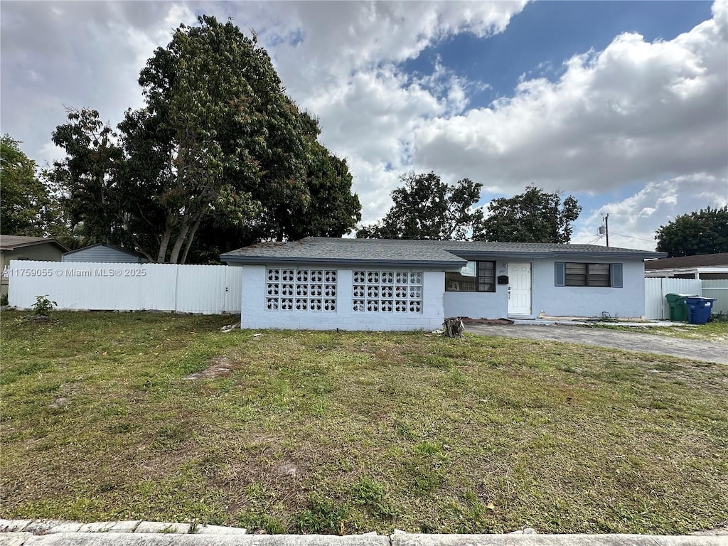 ranch-style home featuring a front lawn and fence