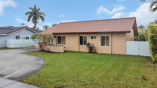 view of front of home with a front lawn, a tiled roof, and stucco siding