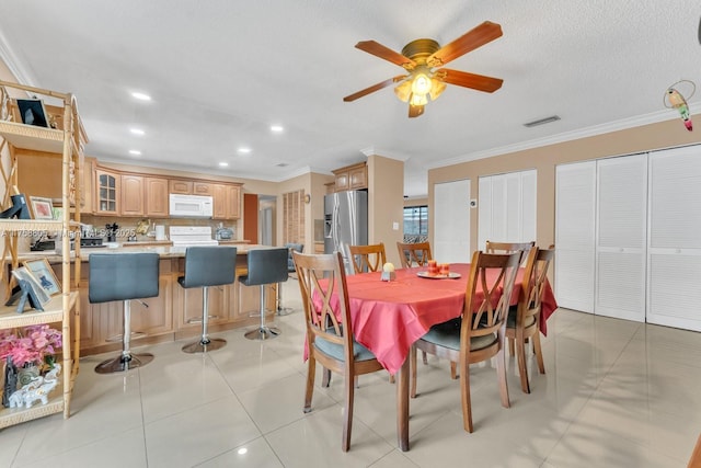 dining space with visible vents, light tile patterned flooring, ceiling fan, a textured ceiling, and crown molding