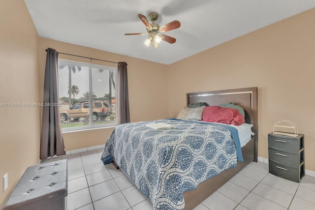 bedroom featuring light tile patterned floors, a textured ceiling, baseboards, and a ceiling fan