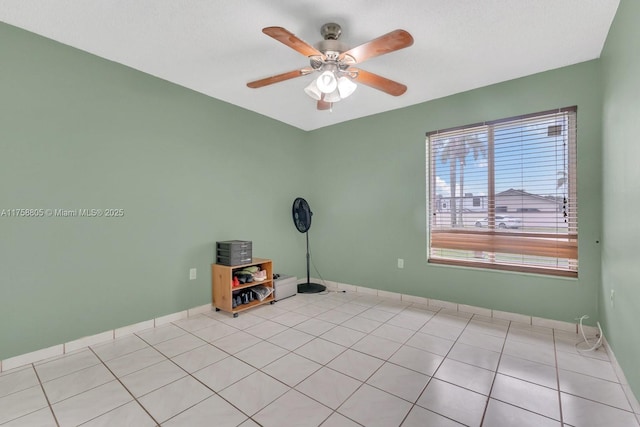 empty room featuring light tile patterned floors, baseboards, and a ceiling fan