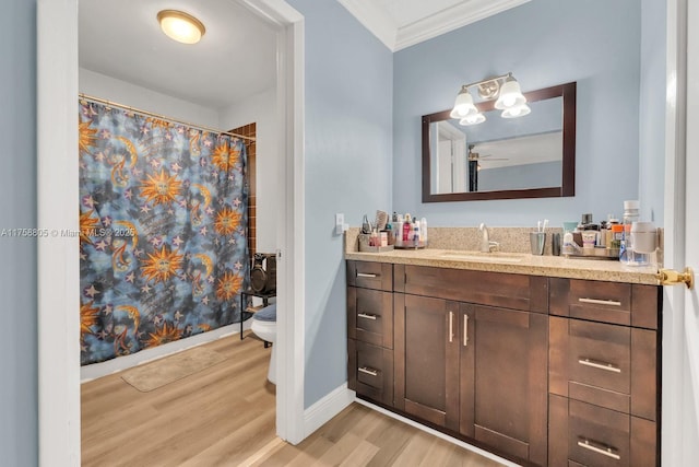 full bath with toilet, wood finished floors, crown molding, baseboards, and vanity