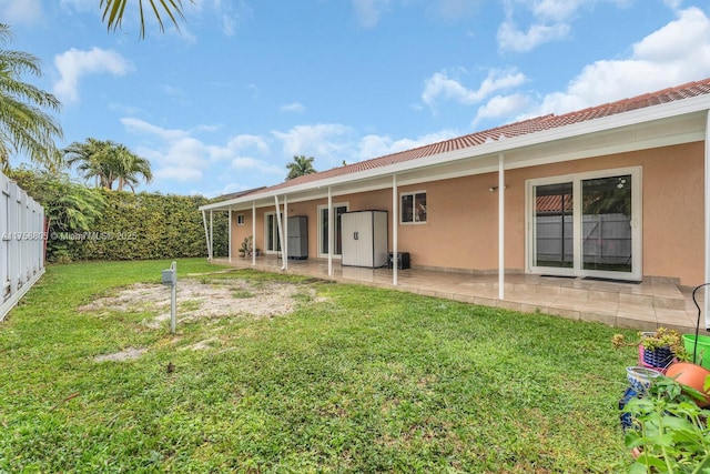 rear view of house with a patio area, stucco siding, a lawn, and fence