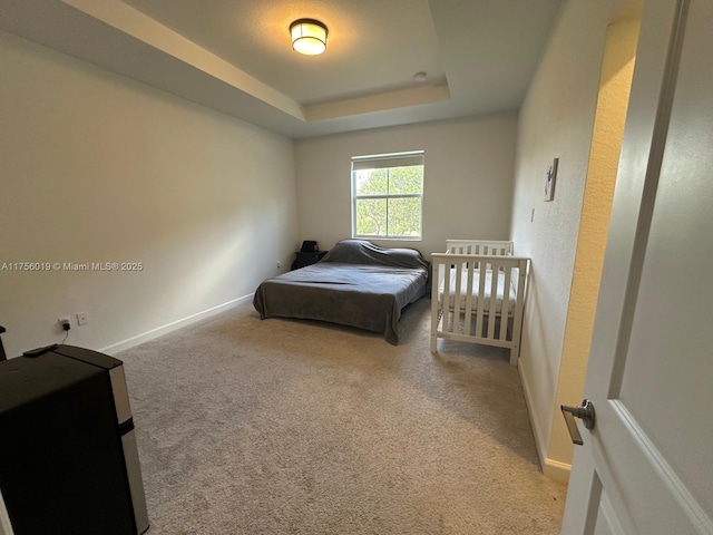 carpeted bedroom with baseboards and a tray ceiling