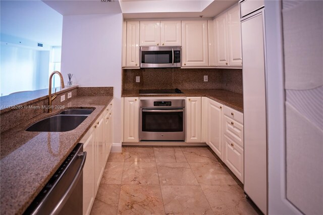 3400 SW 27th Ave Unit 705, Miami, FL 33133 - kitchen featuring appliances with stainless steel finishes, a sink, white cabinets, dark stone countertops, and decorative backsplash
