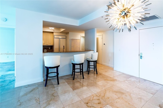 3400 SW 27th Ave Unit 705, Miami, FL 33133 - kitchen with a kitchen bar, a raised ceiling, paneled built in refrigerator, a chandelier, and dark stone counters