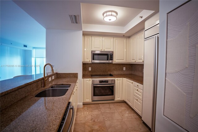 3400 SW 27th Ave Unit 705, Miami, FL 33133 - kitchen featuring stainless steel appliances, a sink, dark stone countertops, white cabinets, and tasteful backsplash