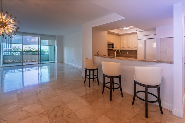 3400 SW 27th Ave Unit 705, Miami, FL 33133 - kitchen featuring paneled built in fridge, baseboards, stainless steel microwave, white cabinetry, and tasteful backsplash