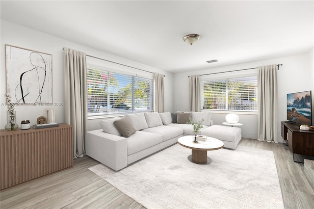 living room featuring radiator, visible vents, and light wood finished floors