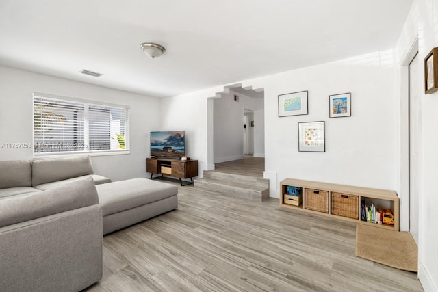 living room featuring light wood finished floors, visible vents, and baseboards