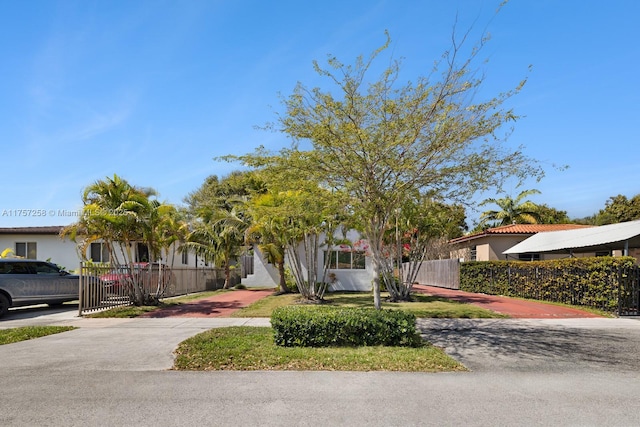 view of property hidden behind natural elements featuring a fenced front yard and stucco siding