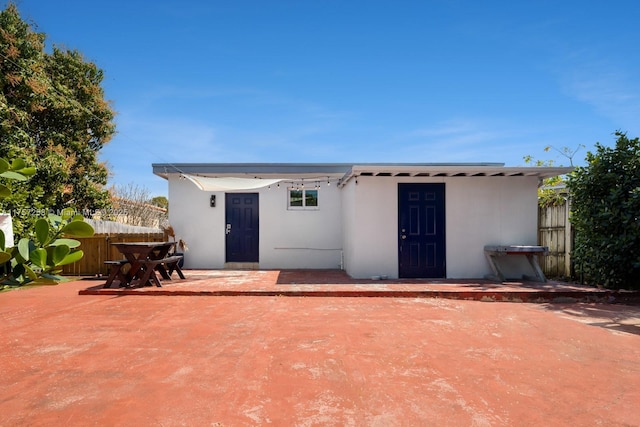 rear view of house featuring stucco siding, a patio, and fence