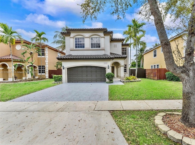 mediterranean / spanish-style home with decorative driveway, stucco siding, a front yard, fence, and a garage