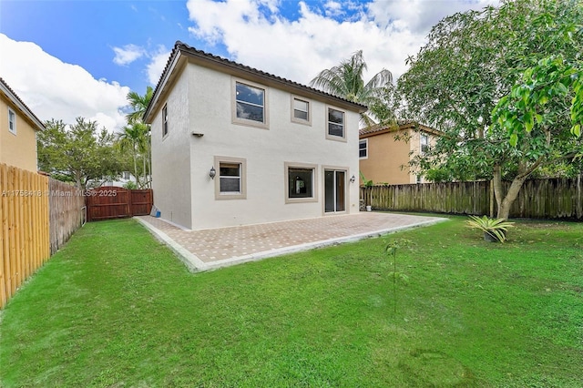 back of house featuring a fenced backyard, a yard, a patio, and stucco siding